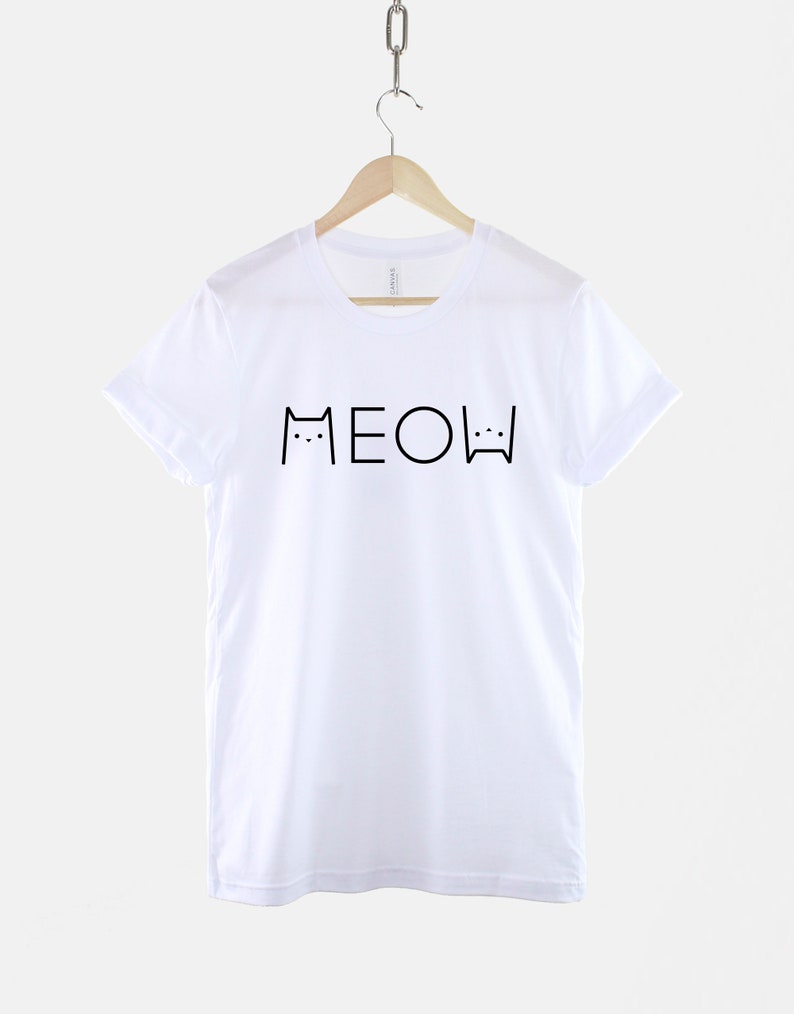 May include: White t-shirt with black text that says "MEOW" with cat ears and whiskers on either side of the word.