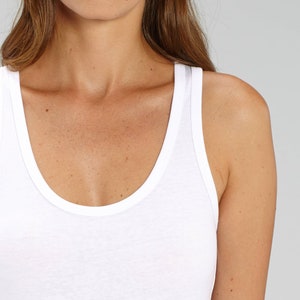 May include: White sleeveless tank top with a scoop neck.