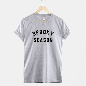 Puede incluir: Una camiseta gris jaspeada con texto negro que dice "Spooky Season".