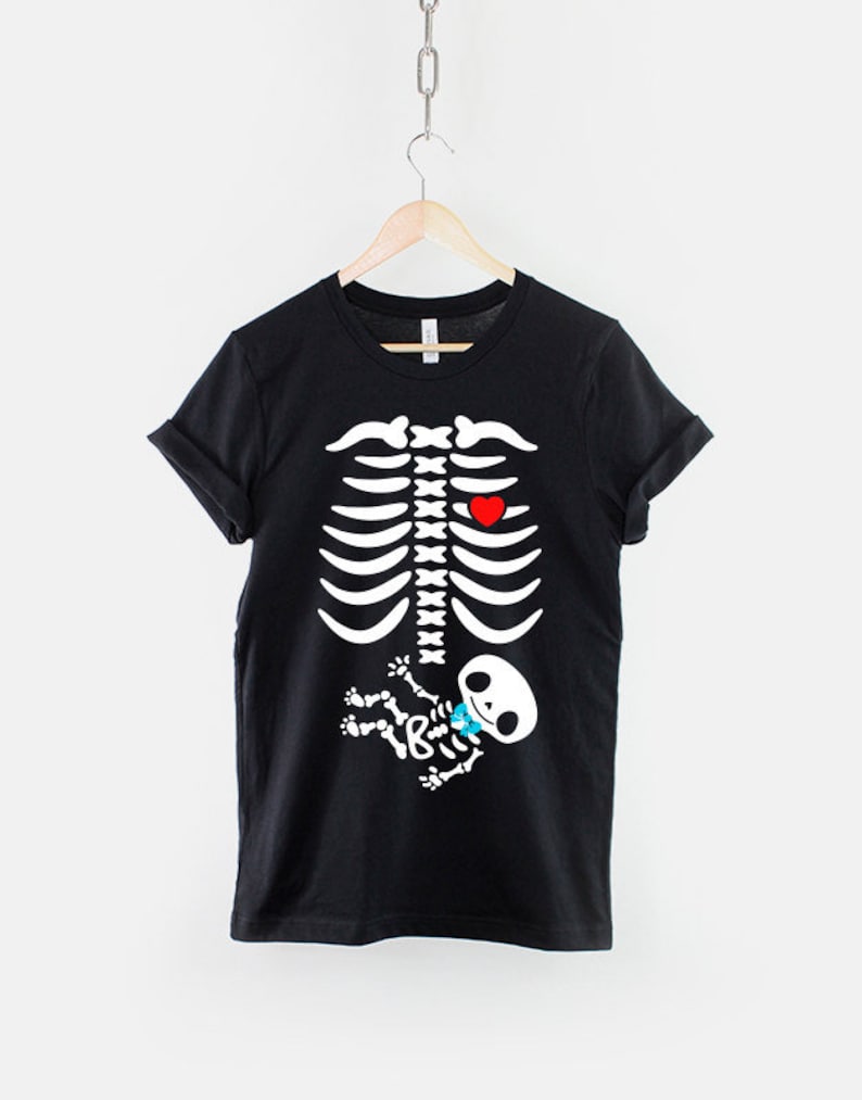 May include: Black t-shirt with a white skeleton graphic. The skeleton has a red heart and a small white skeleton baby inside the ribcage.