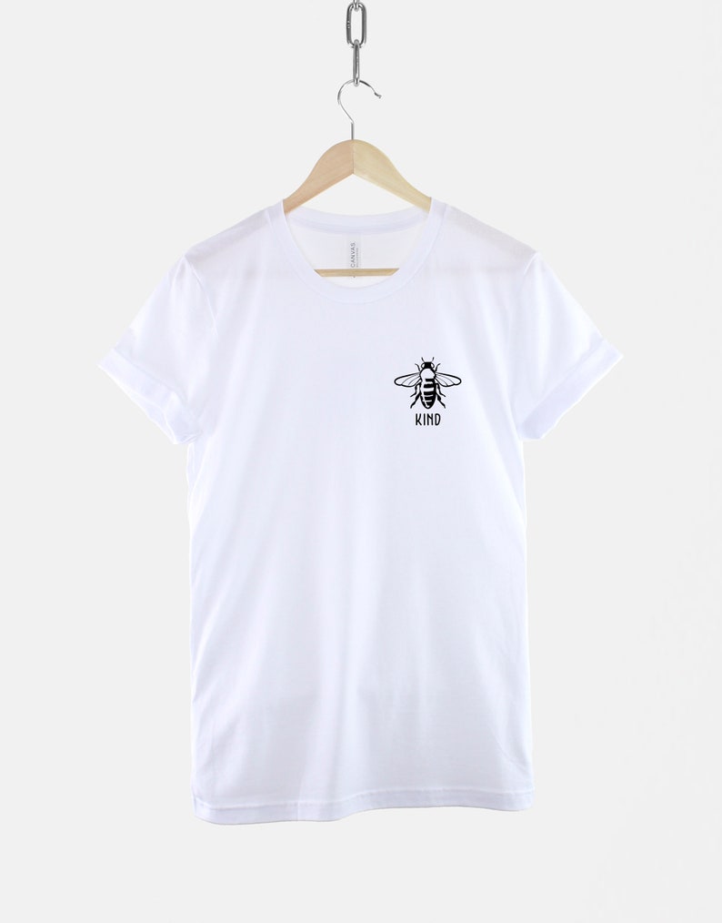 Op de afbeelding: Wit T-shirt met een zwarte bij-afbeelding en het woord "KIND" eronder.
