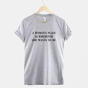 May include: A gray t-shirt with the text "A woman's place is wherever she wants to be."
