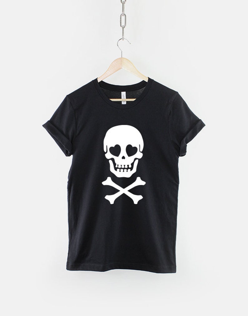 May include: Black t-shirt with a white skull and crossbones design. The skull has heart-shaped eyes.