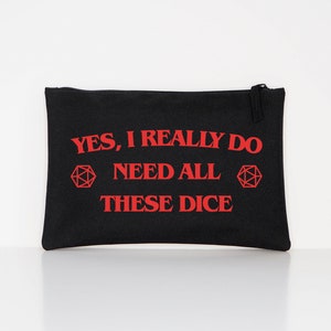 Puede incluir: Bolsa con cremallera de lona negra con texto rojo que dice "YES, I REALLY DO NEED ALL THESE DICE" y un gr&aacute;fico de dados poli&eacute;dricos rojos. La bolsa es rectangular y tiene una cremallera negra.