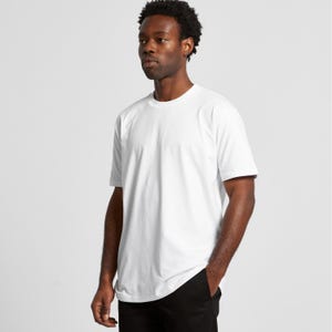 A man wearing a white t-shirt stands against a plain background.