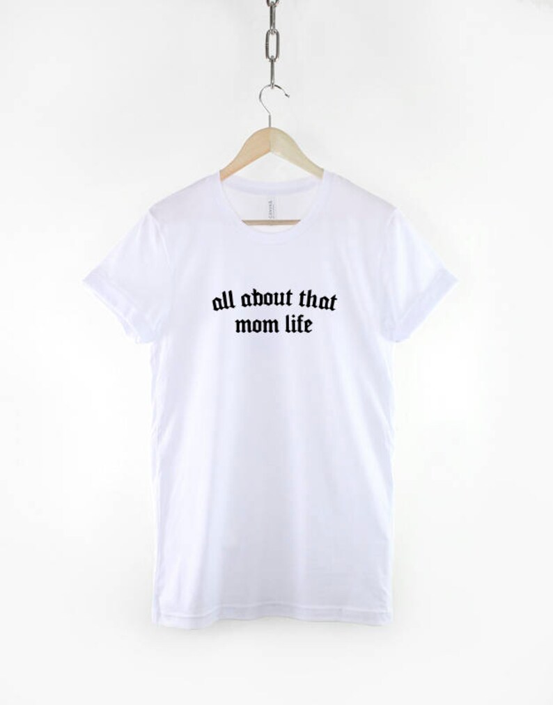 May include: White t-shirt with black text that reads "all about that mom life" in a gothic font.