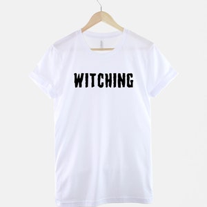 May include: White t-shirt with black text that reads "Witching" in a distressed font.