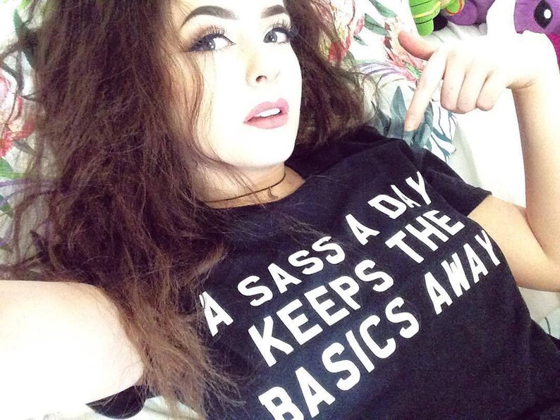 May include: A black t-shirt with white text that reads "A Sass A Day Keeps The Basics Away".