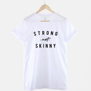 May include: White t-shirt with black text that reads "STRONG -not- SKINNY".