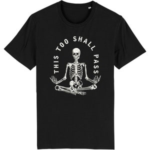 May include: Black t-shirt with a white skeleton sitting in a yoga pose. The skeleton is surrounded by a circle with the text "This too shall pass".