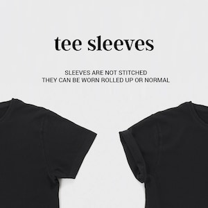 Op de afbeelding: Twee zwarte T-shirts met korte mouwen. De mouwen van het rechter T-shirt zijn opgerold. De tekst "tee sleeves" en "Sleeves are not stitched. They can be worn rolled up or normal" wordt boven de T-shirts weergegeven.