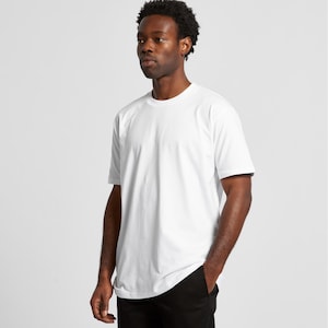 A man wearing a white t-shirt stands against a plain background.