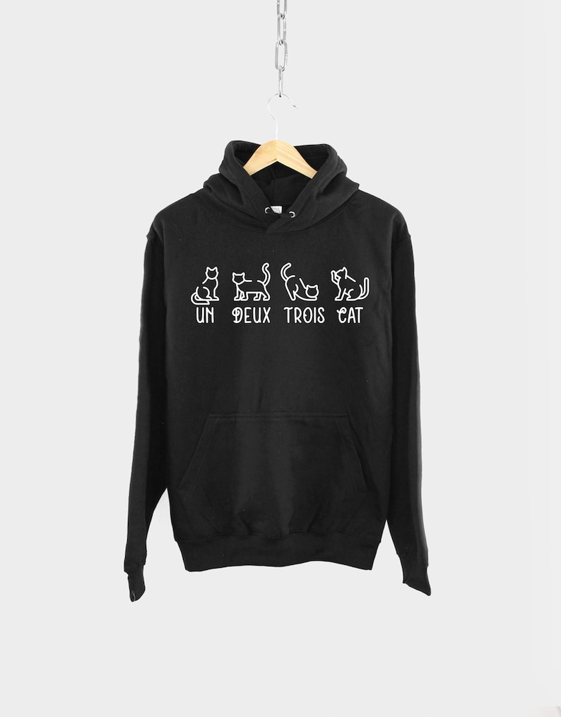 May include: Black hooded sweatshirt with a white graphic of cats and the text "UN DEUX TROIS CAT".