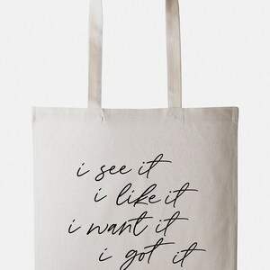 May include: A white canvas tote bag with black text that reads "i see it i like it i want it i got it".