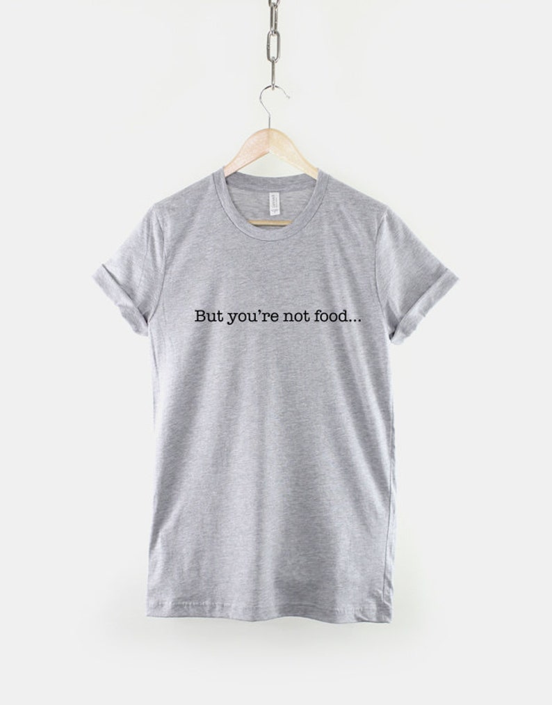 Może przedstawiać: Szary t-shirt z nadrukiem "But you're not food..." w kolorze czarnym.