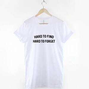 May include: White t-shirt with black text that reads "Hard to find Hard to forget".