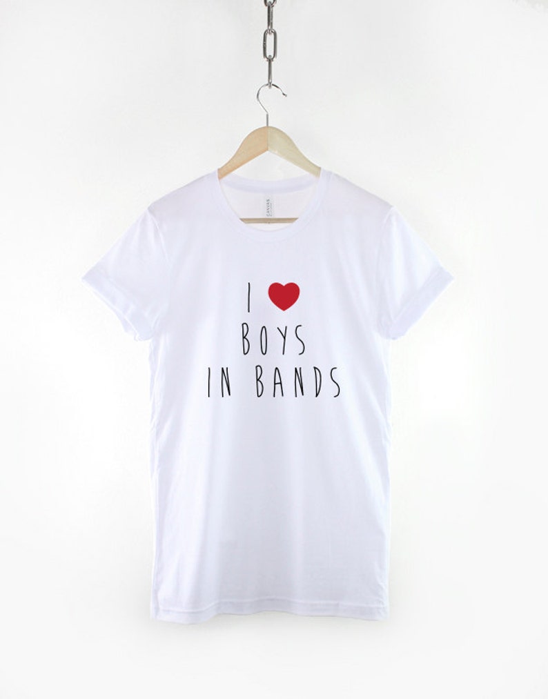 May include: White t-shirt with a red heart and the text "I love boys in bands" printed on the front.