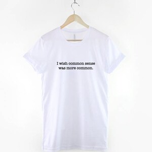 May include: White t-shirt with black text that reads "I wish common sense was more common."