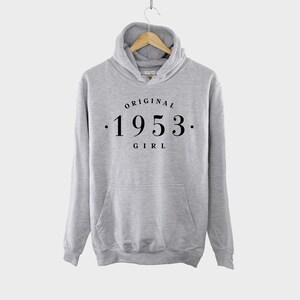 May include: Gray hooded sweatshirt with the text "ORIGINAL . 1953 . GIRL" printed on the front.