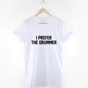 Puede incluir: Camiseta blanca con texto negro que dice "Prefiero al baterista".