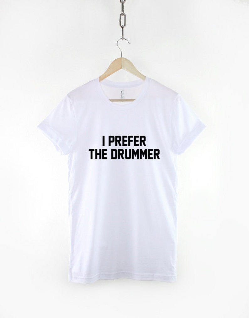 Puede incluir: Camiseta blanca con texto negro que dice "Prefiero al baterista".