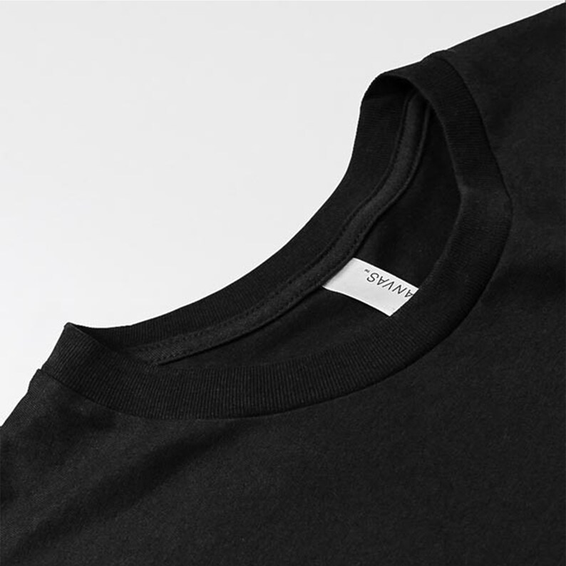 May include: Close-up of the neckline of a black t-shirt with a white tag that reads "ANVAS".