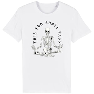 May include: White t-shirt with a black skeleton sitting in a meditative pose with the text "This Too Shall Pass" around it.