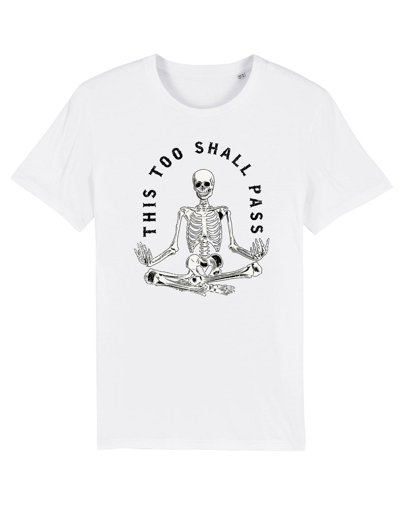May include: White t-shirt with a black skeleton sitting in a meditative pose with the text "This Too Shall Pass" around it.