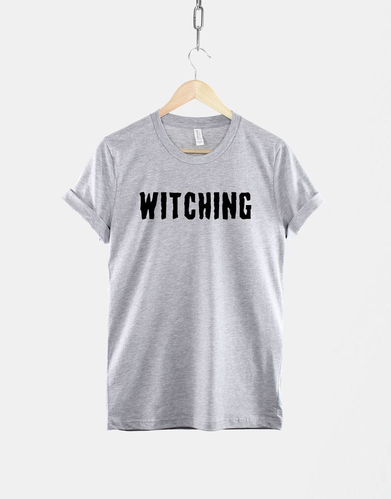 May include: A heather grey t-shirt with the word "Witching" printed in black on the front.
