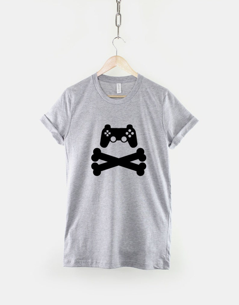 May include: A gray t-shirt with a black graphic of a video game controller and crossed bones.