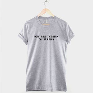 K&ouml;nnte beinhalten: Ein hellgraues T-Shirt mit dem Aufdruck "Don't call it a dream, call it a plan" in Schwarz.