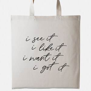 May include: A white canvas tote bag with black text that reads "i see it i like it i want it i got it".