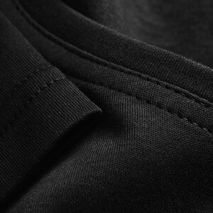 A close-up view of a black fabric, possibly a shirt or garment, with a textured and wrinkled appearance.