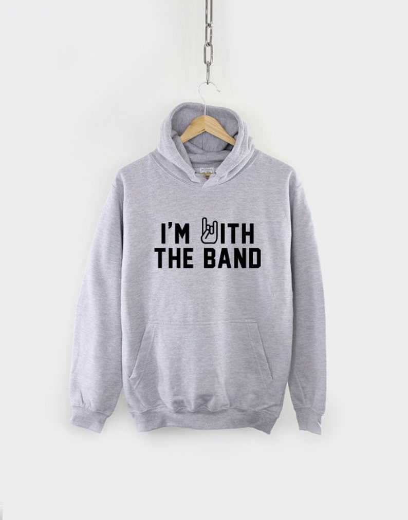 Puede incluir: Una sudadera con capucha gris con un gr&aacute;fico negro que dice "I'm with the band" y un gesto de mano de rock and roll.