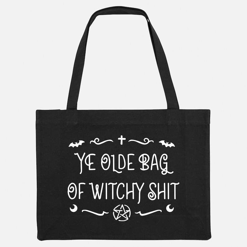 Puede incluir: Bolsa de tela negra con texto blanco que dice "Ye Olde Bag of Witchy Shit". El texto est&aacute; rodeado por un borde decorativo con murci&eacute;lagos, una cruz, una luna creciente y un pentagrama.