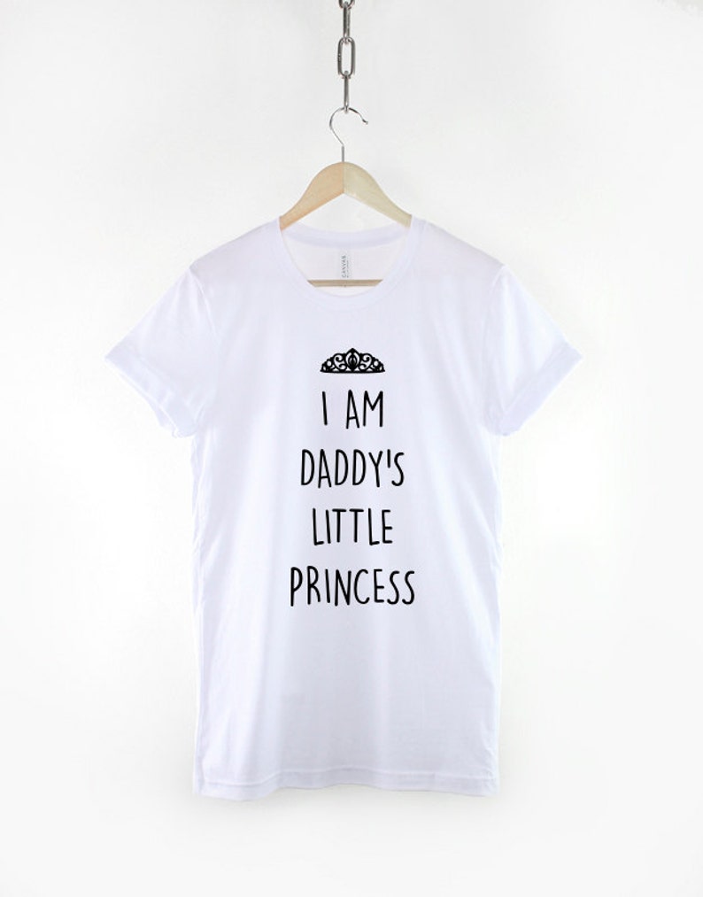 May include: White t-shirt with black text that reads "I am Daddy's Little Princess" and a small crown graphic above the text.