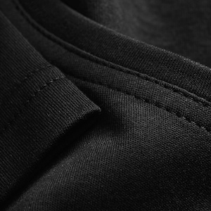 A close-up view of a black fabric, possibly a shirt or garment, with a textured and wrinkled appearance.