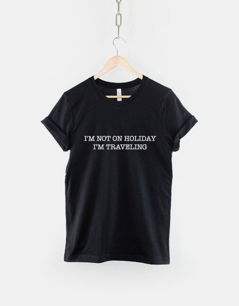 May include: Black t-shirt with white text that reads "I'm not on holiday I'm traveling".