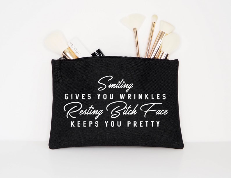 May include: Black cosmetic bag with the text "Smiling gives you wrinkles, Resting Bitch Face keeps you pretty" in white script. The bag is filled with makeup brushes and a tube of "Velour" brand makeup.