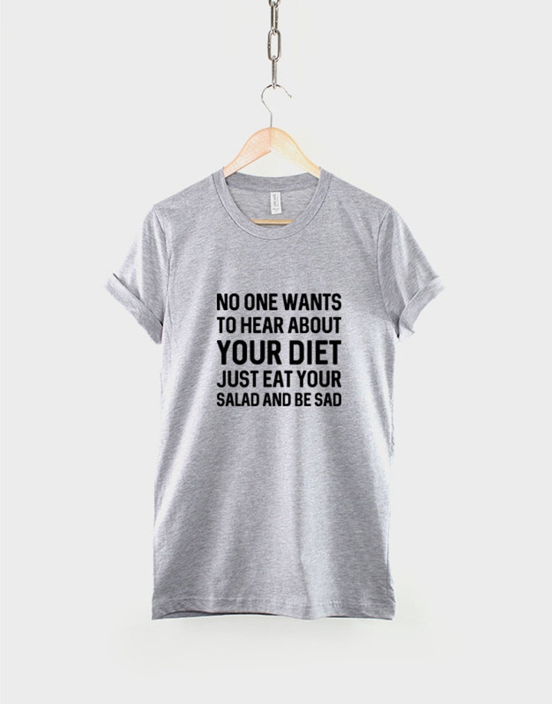 May include: Gray t-shirt with black text that reads "NO ONE WANTS TO HEAR ABOUT YOUR DIET JUST EAT YOUR SALAD AND BE SAD"