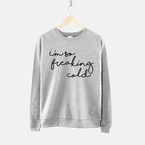 May include: A gray sweatshirt with the text "i'm so freaking cold" written in black.
