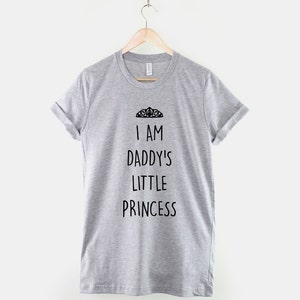 May include: Gray t-shirt with the text "I am Daddy's Little Princess" and a crown graphic.