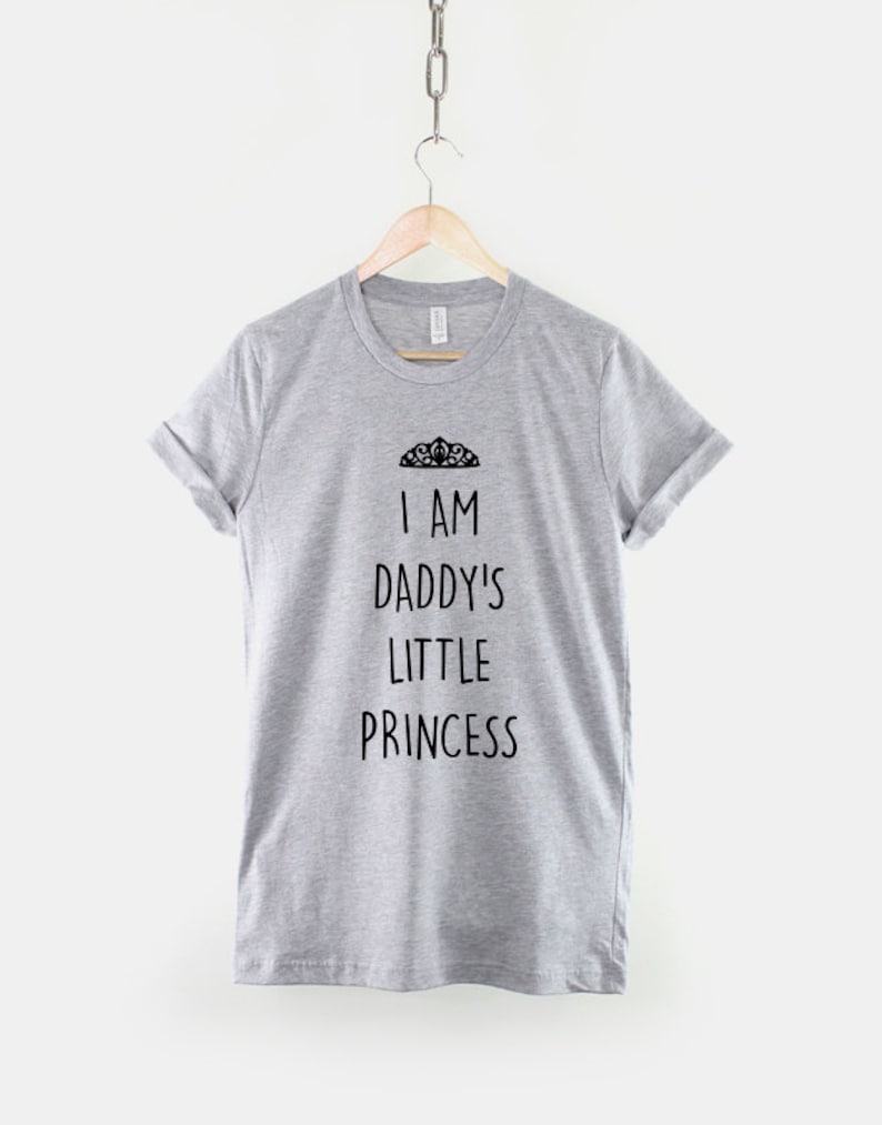 May include: Gray t-shirt with the text "I am Daddy's Little Princess" and a crown graphic.