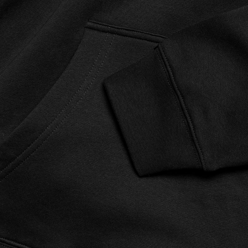 A close-up view of a black hoodie, showing the fabric and details of the garment.
