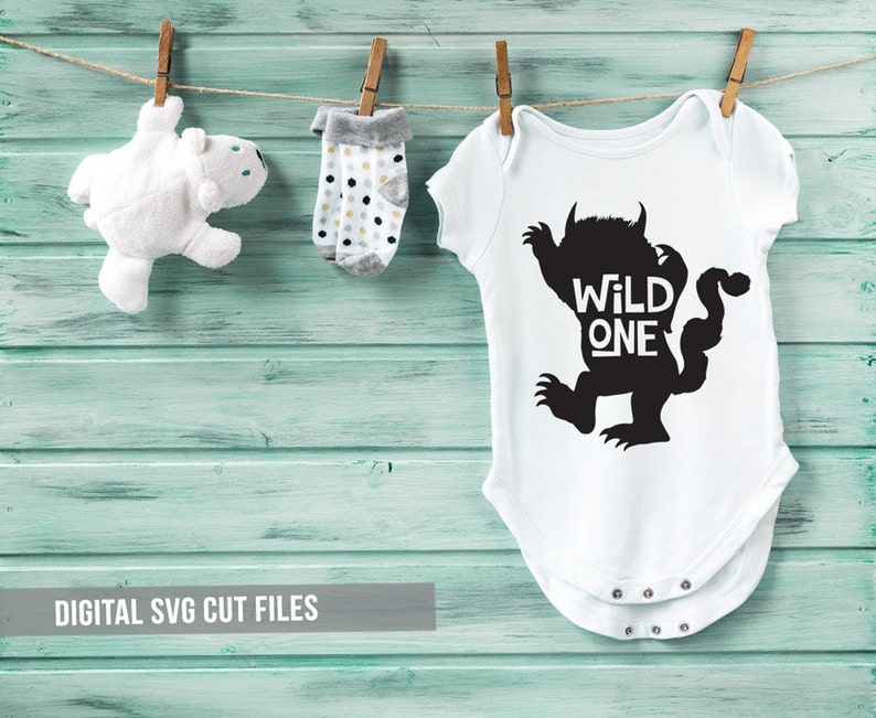K&ouml;nnte beinhalten: Ein wei&szlig;er Baby-Body mit einer schwarzen Monstergrafik und dem Schriftzug "WILD ONE". Er h&auml;ngt an einer W&auml;scheleine zusammen mit einem wei&szlig;en Teddyb&auml;r und Socken mit Polka Dots. Der Hintergrund ist eine hellblaue Holzwand, mit dem Text "DIGITAL SVG CUT FILES".