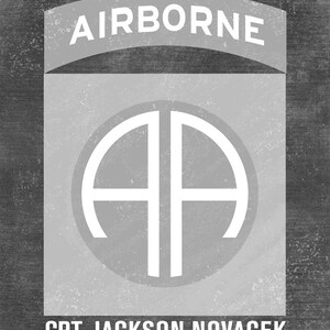 May include: A black and white image of a military patch with the words "AIRBORNE" at the top and "CPT JACKSON NOVACEK" at the bottom. The patch features a white circle with the letters "AA" inside.