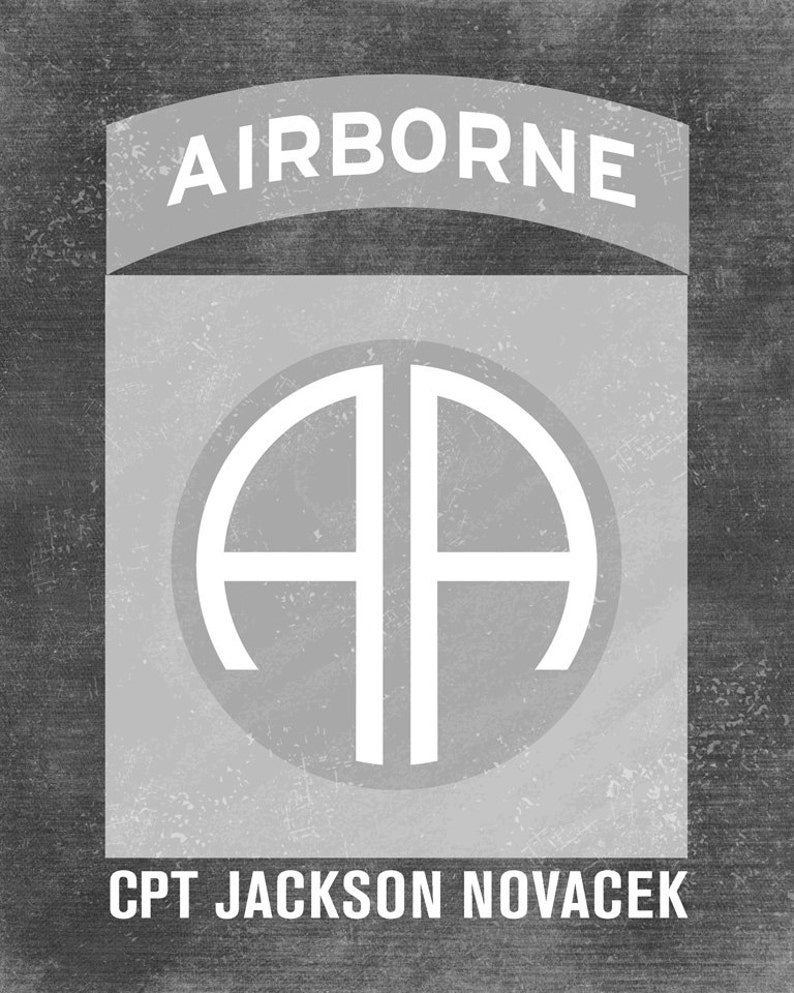 May include: A black and white image of a military patch with the words "AIRBORNE" at the top and "CPT JACKSON NOVACEK" at the bottom. The patch features a white circle with the letters "AA" inside.