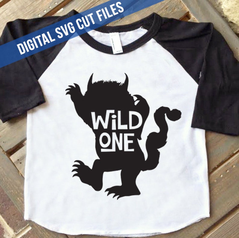 K&ouml;nnte beinhalten: Wei&szlig;es und schwarzes Raglan-T-Shirt mit schwarzer Monster-Silhouette und dem wei&szlig;en Schriftzug "WILD ONE". Oben befindet sich ein blaues Banner mit dem Text "DIGITAL SVG CUT FILES".