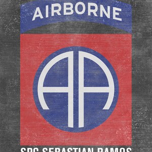 May include: A red and blue military patch with the text "AIRBORNE" above a white circle with the letters "AA" inside. The text "SPC SEBASTIAN RAMOS" is below the circle.
