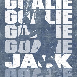 May include: A white graphic design with the word "GOALIE" repeated five times, with the word "JACK" in the middle. The graphic is overlaid on a blue background with a silhouette of a lacrosse player holding a lacrosse stick.